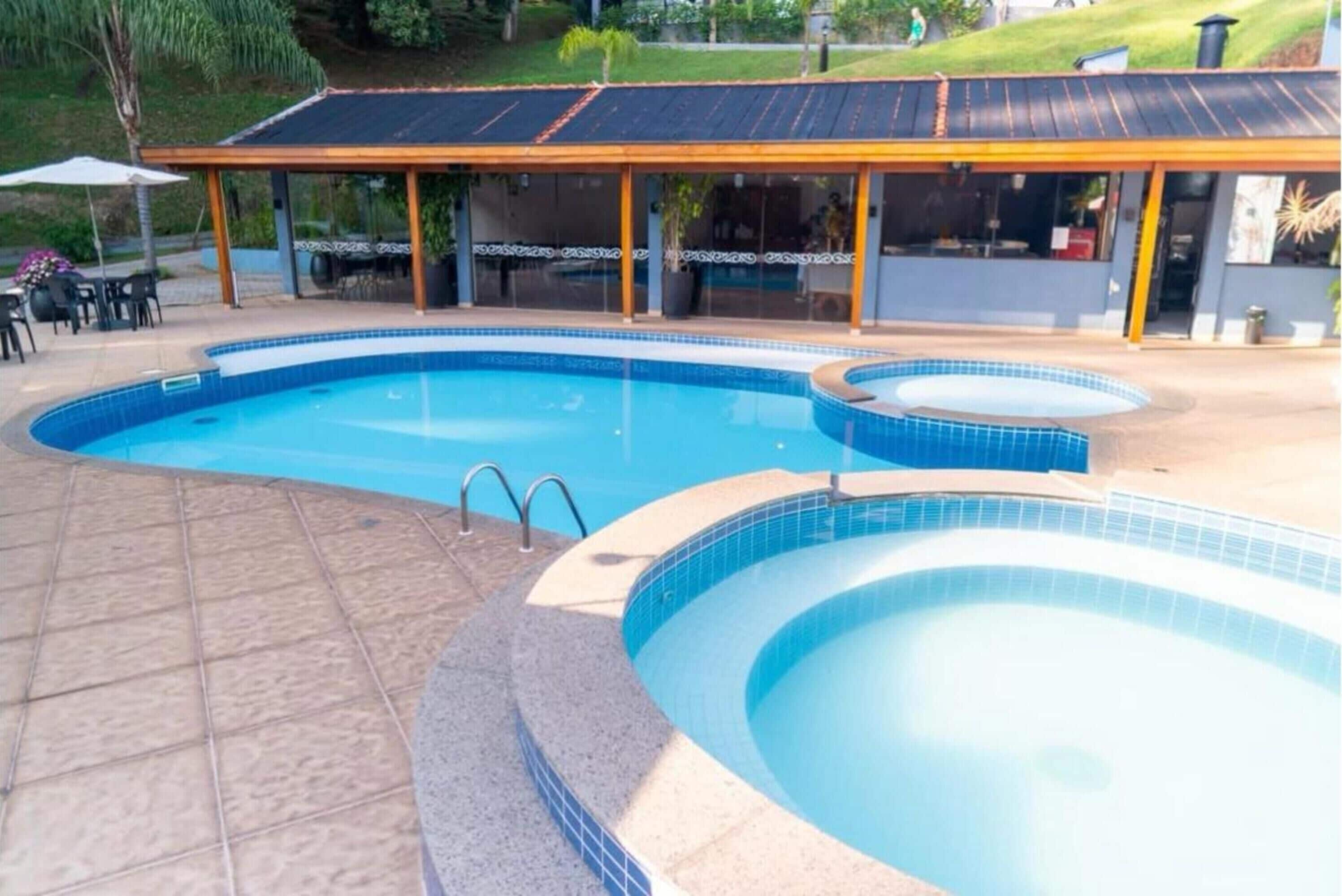 Una piscina con solarium e zona relax coperta.