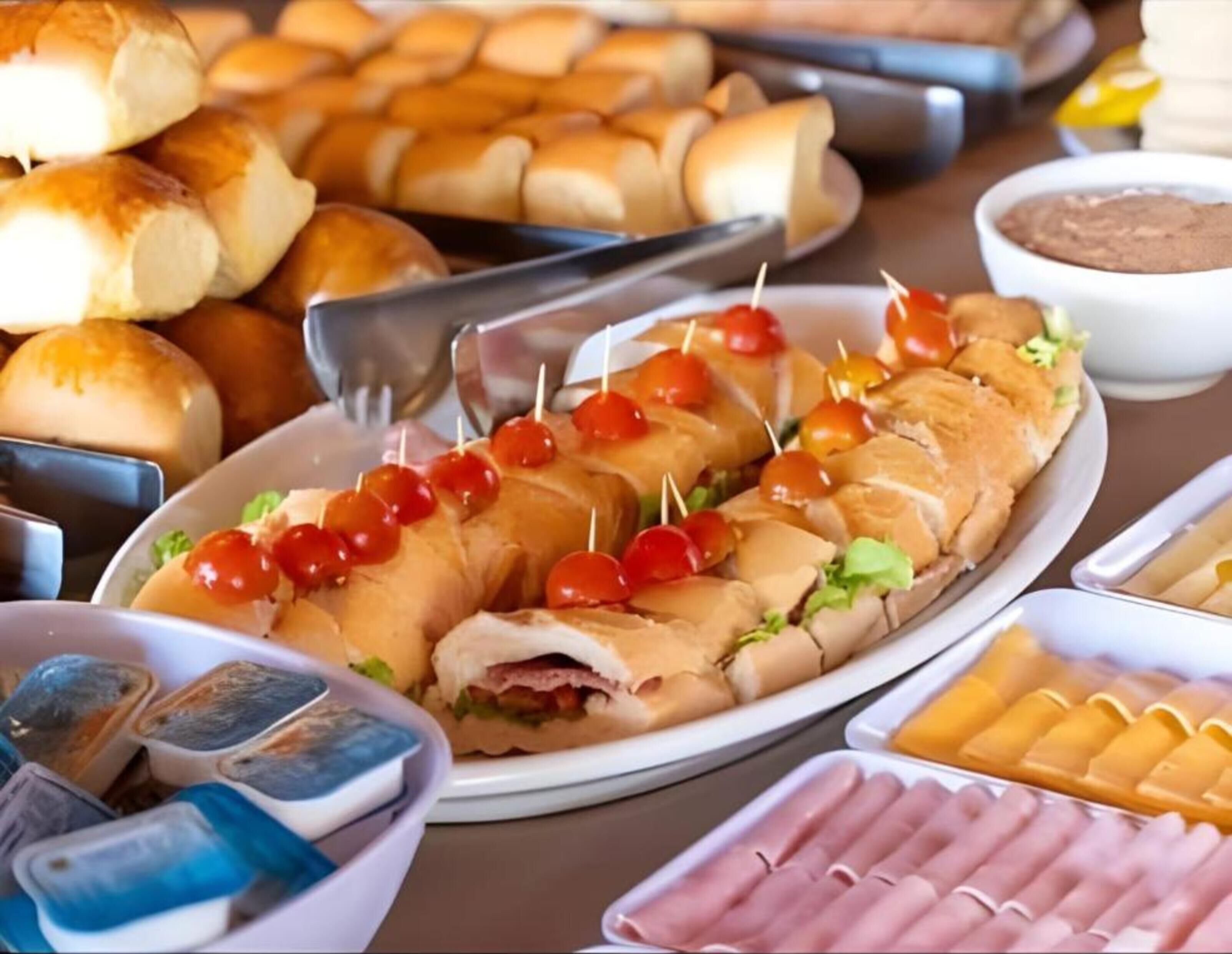 A buffet table with various food items including sandwiches, rolls, and containers of dips.