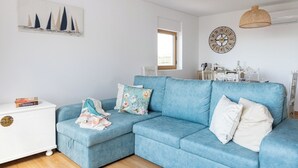 Un salon moderne avec un canapé bleu, une table d’appoint blanche et une horloge murale décorative.