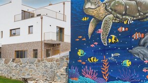 Un bâtiment moderne doté d’une façade en pierre, d’un balcon et d’une fresque représentant une tortue entourée d’animaux marins.