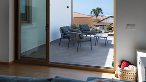 Une pièce dotée d’une porte-fenêtre coulissante donnant sur un patio extérieur aménagé avec une table et des chaises.