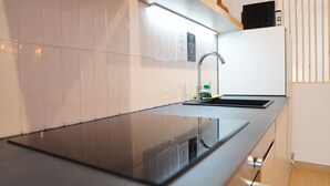 A modern kitchen with a black countertop, stainless steel sink, and a microwave on the countertop.