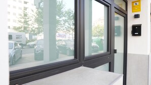 A modern building entrance with a glass door reflecting parked cars and a street view.