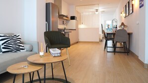 A modern living room with a sofa, a round coffee table, a chair, and a dining area with a table and chairs.