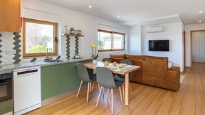 Eine moderne Küche mit grünen Schränken, einem Holzespeisetisch und einem braunen Sofa.