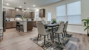 A modern kitchen with a dining area, wooden cabinets, and a central island.