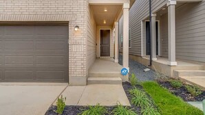 A residential building with a garage, a covered walkway, and a small garden area.