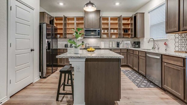 A modern kitchen with a central island, built-in cabinets, and a microwave.