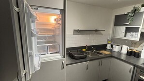 Una cocina moderna con refrigerador empotrado, un lavamanos y una encimera con un tostador y otros electrodomésticos.