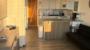 Una cocina compacta con armarios blancos, una encimera de madera y un microondas integrado.