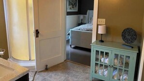 A room with a bed, a cabinet with glass doors, and a door leading to another room.