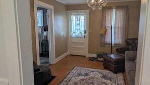 A living room with a patterned rug, a brown leather chair, and a chandelier.