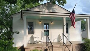 A single-story house with a porch, a flag, and a small garden area.