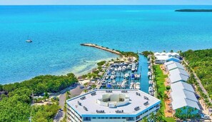 An aerial view of a coastal hotel with a marina, a pier, and lush greenery.