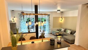 Una sala moderna con sofá, un comedor con mesa y una cocina con estufa.
