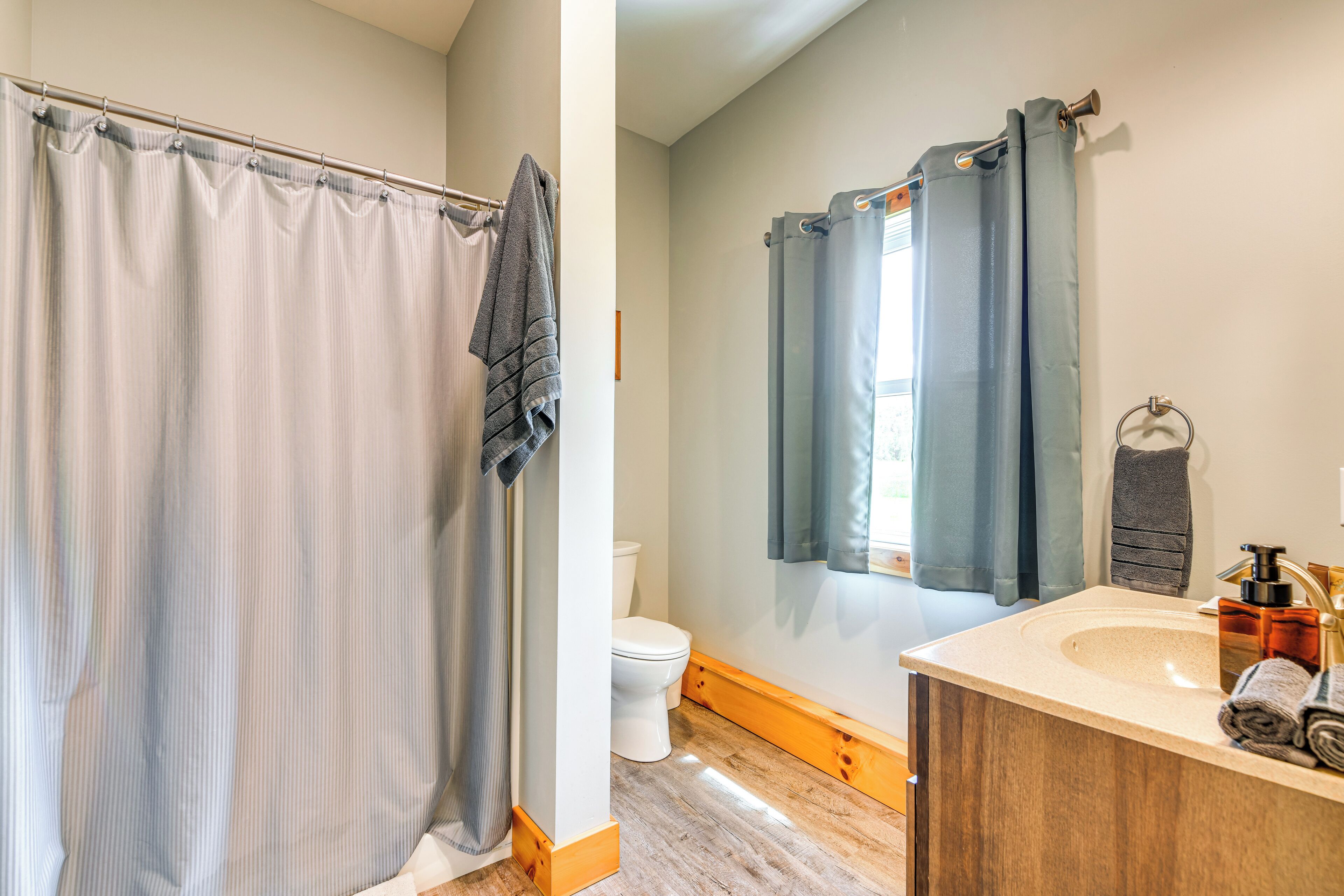 A bathroom with a shower curtain, toilet, sink, and towel rack.
