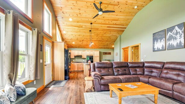 A spacious living room with a leather sectional sofa, wooden flooring, and a ceiling fan. - Mtn-View Home 6 Mi to Jay Peak Resort: Fish & Hike (Montgomery Center)