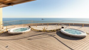 Una terraza con dos jacuzzis con vistas a una playa y al mar.