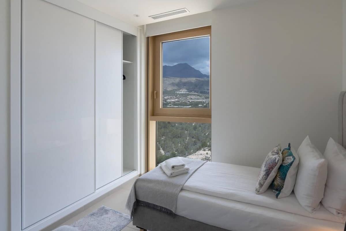Ein Schlafzimmer mit einem Bett, einem Fenster mit Bergblick und einem Kleiderschrank.