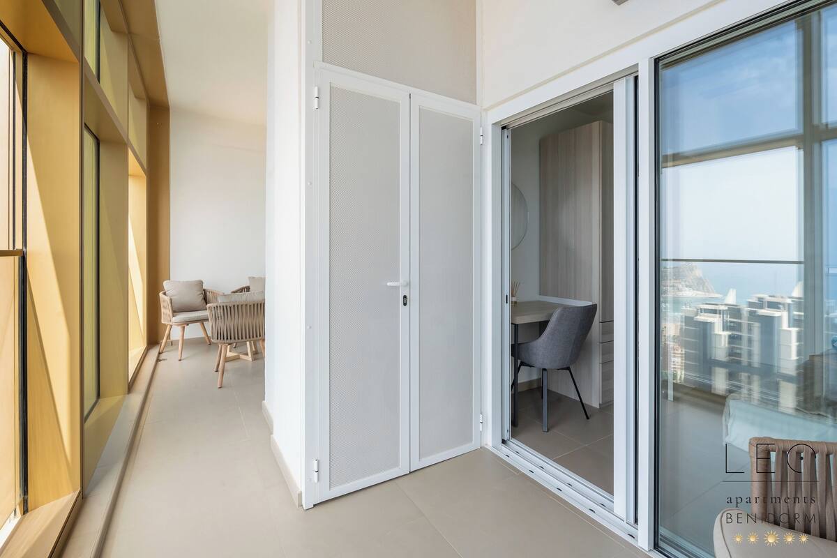 Ein modernes Apartment mit einer Schiebetür zum Balkon, einem Essbereich und Blick auf die Stadtlandschaft.