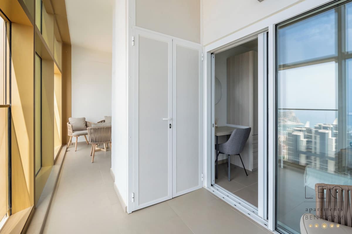 Un appartamento moderno con una porta scorrevole in vetro che dà su un balcone, una zona pranzo e vista sulla città.