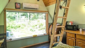 Una cocina acogedora con un amplio ventanal, techo de madera y una escalera.