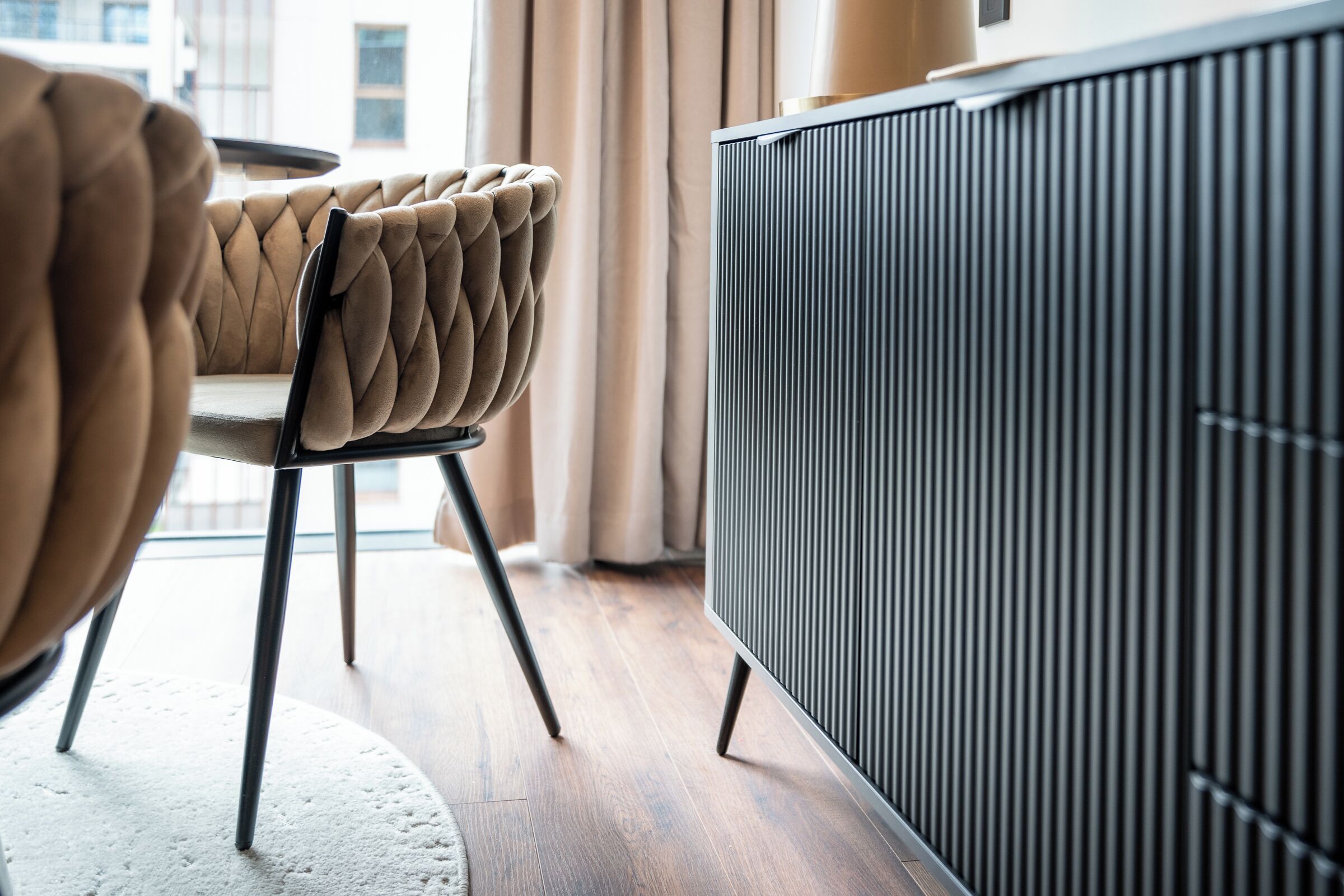 A modern living room with a tufted leather sofa, a black-framed television, and a radiator.