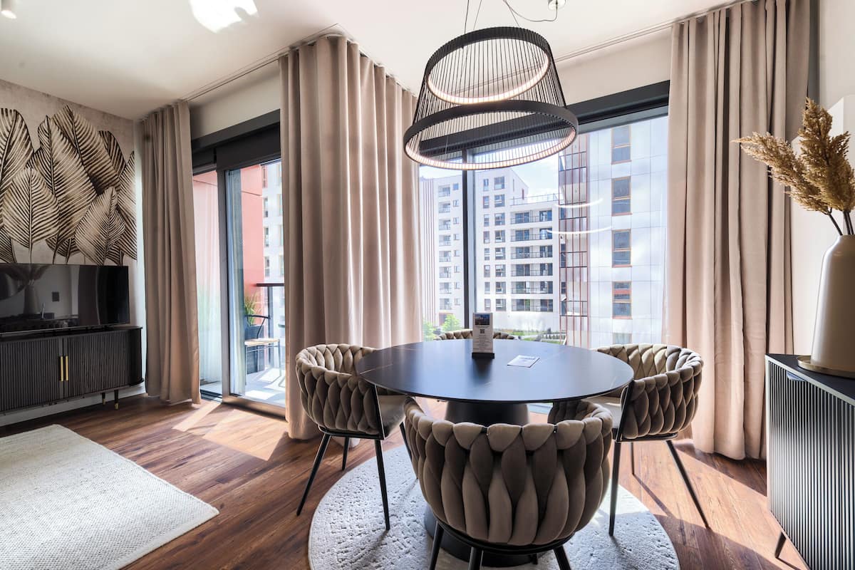 Un espace repas moderne avec une table ronde, des chaises rembourrées et un luminaire suspendu.