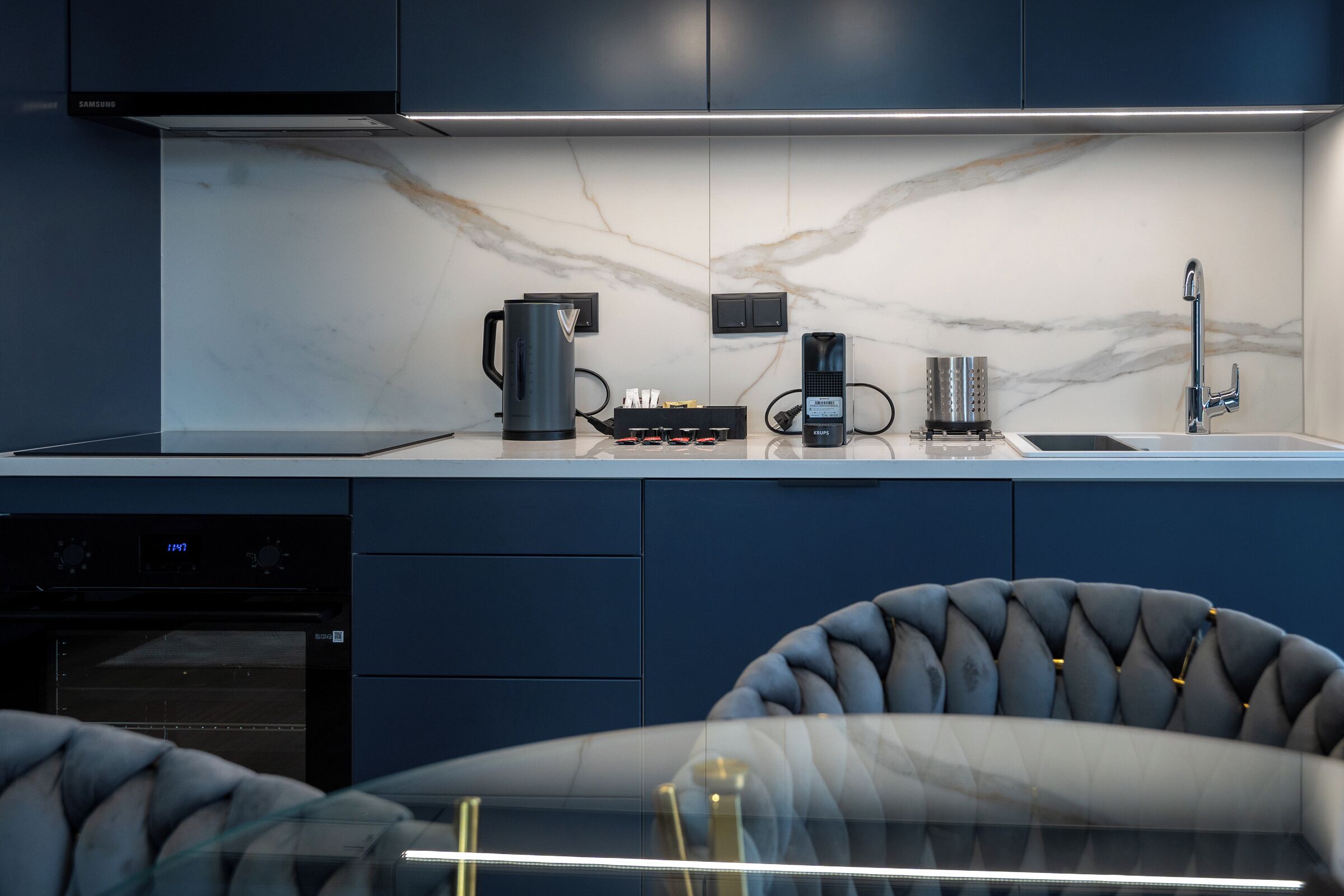 A modern kitchen with a built-in oven, a coffee maker, and a kettle.