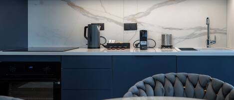 Una cucina moderna con forno integrato, macchina del caffè e bollitore.