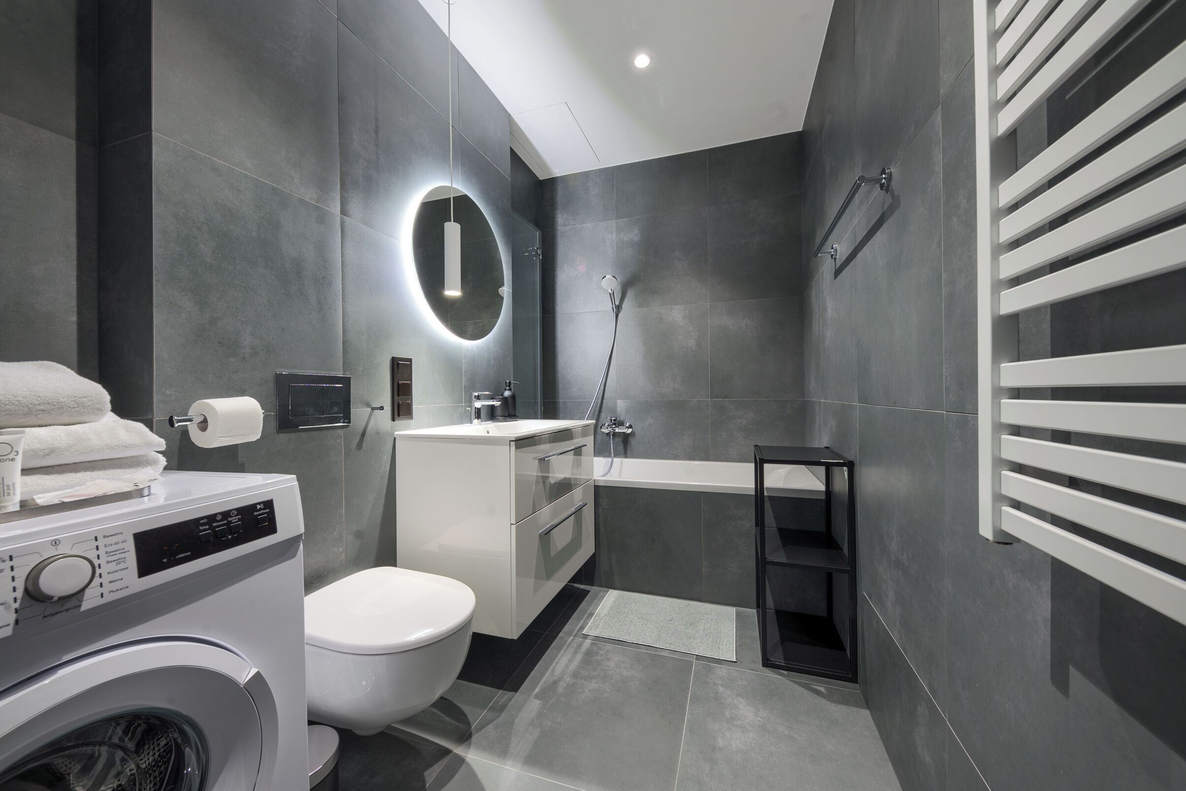 Un bagno moderno con lavatrice, WC, lavandino e vasca da bagno.