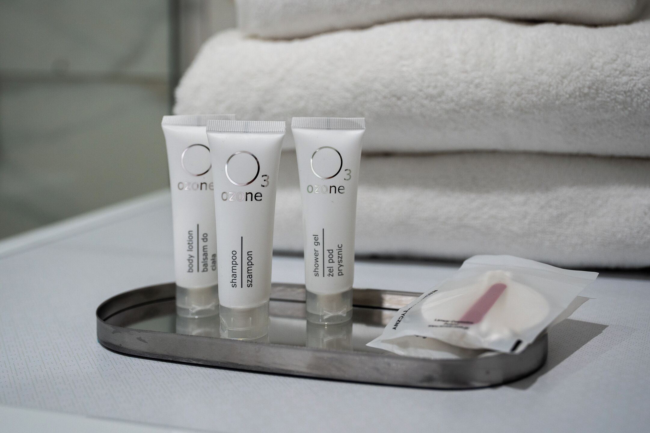 Drie tubes Ozone bodylotion, een douchegel en een pakje doekjes op een dienblad.