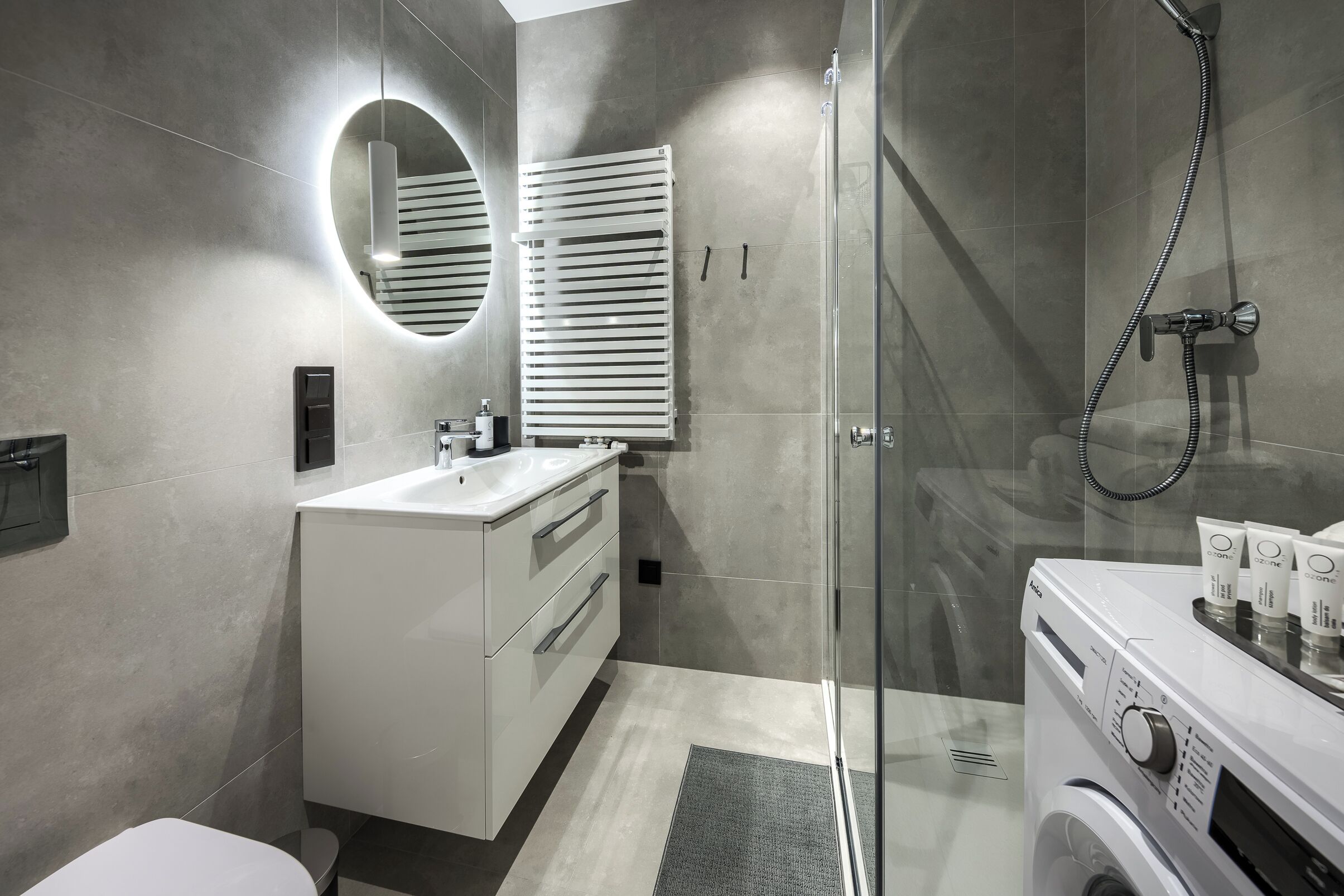 A modern bathroom with a glass shower enclosure, a built-in sink, and a washing machine.