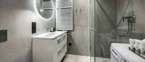 A modern bathroom with a glass shower enclosure, a built-in sink, and a washing machine.