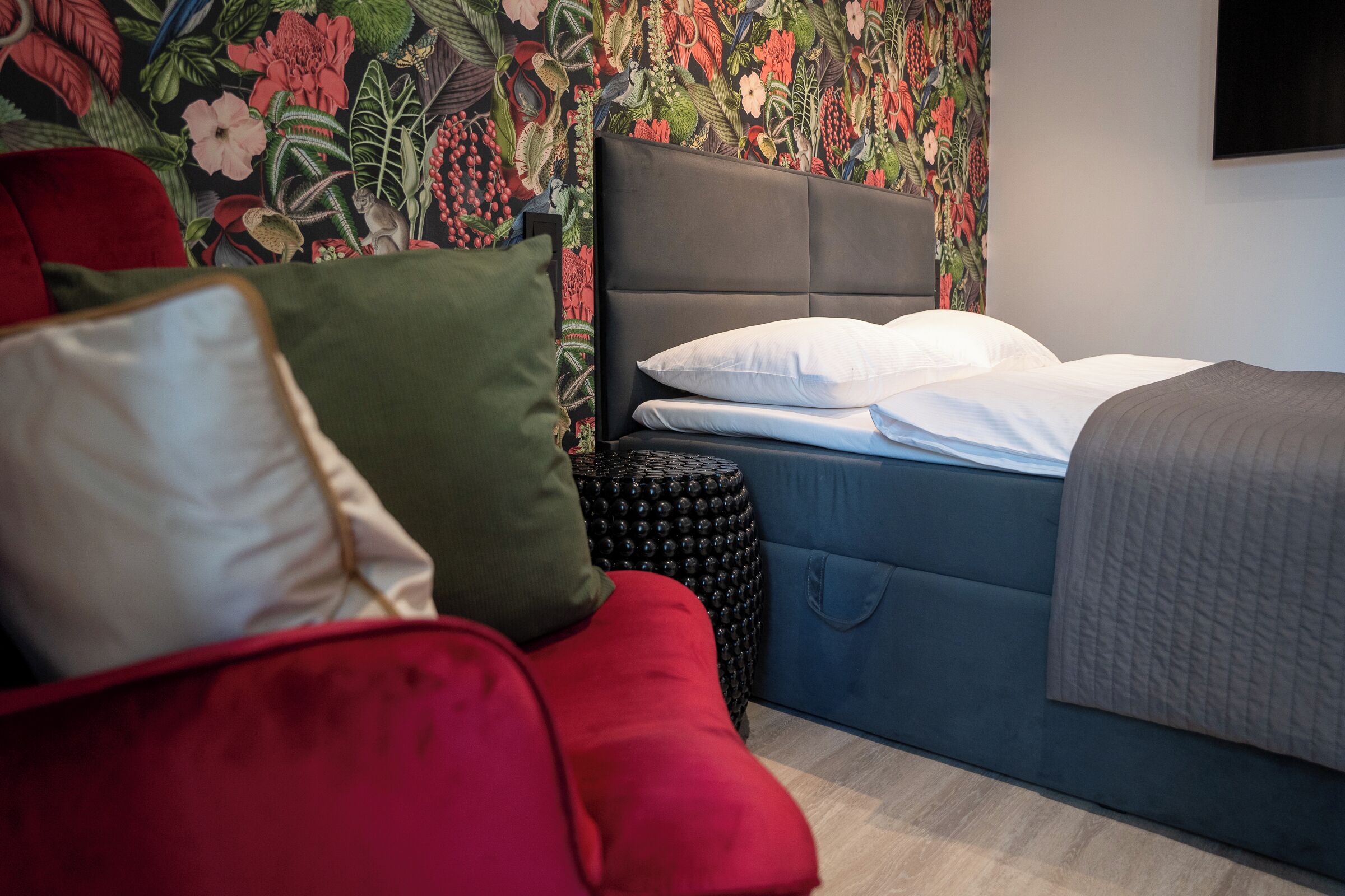 Una camera da letto moderna con un letto, un divano rosso e una parete decorativa.