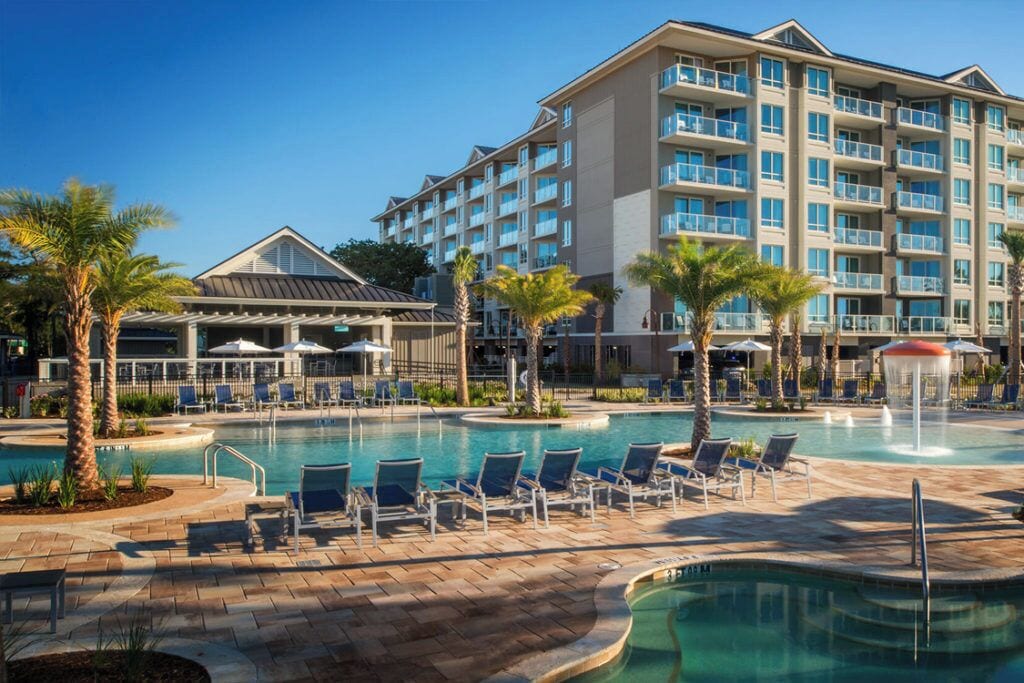 Ein Hotel mit Poolbereich, inklusive Liegestühlen und Sonnenschirmen.