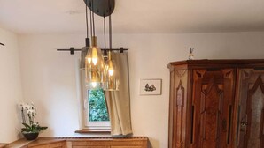 A wooden dining table with bench seating, a pendant light fixture, and a cabinet with intricate woodwork.
