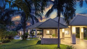 A modern resort with multiple villas, a swimming pool, and lush tropical landscaping.