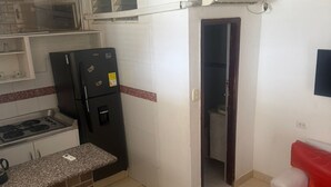 A compact kitchen with a refrigerator, stove, and a small countertop. - Studio apartment near the 👙👙🏖️ wing (Santa Marta)