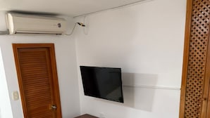 A room with a wooden wardrobe, a TV mounted on the wall, a red and white sofa, and a tiled floor. - Studio apartment near the 👙👙🏖️ wing (Santa Marta)
