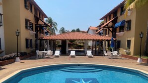 A swimming pool with a star mosaic design, surrounded by lounge chairs and a covered seating area.