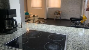A modern kitchen with a built-in stove, a coffee maker, and a dining area with a table and chairs.