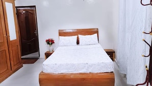 Un dormitori amb llit de fusta, cortines blanques i un armari de fusta.