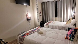 A hotel room with two beds, a TV mounted on the wall, and a window with curtains. - Oasis Inka Machupicchu (Aguas Calientes)