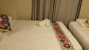 A hotel room with two beds, each with a colorful embroidered pillow and a neatly folded towel. - Oasis Inka Machupicchu (Aguas Calientes)