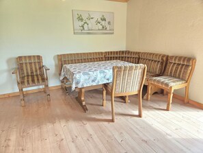 A room with a wooden floor, a table with a patterned tablecloth, and a bench with striped upholstery. - Quiet vacation apartment for 2 persons or more with fully equipped kitchen + washing machine (Ilshofen)