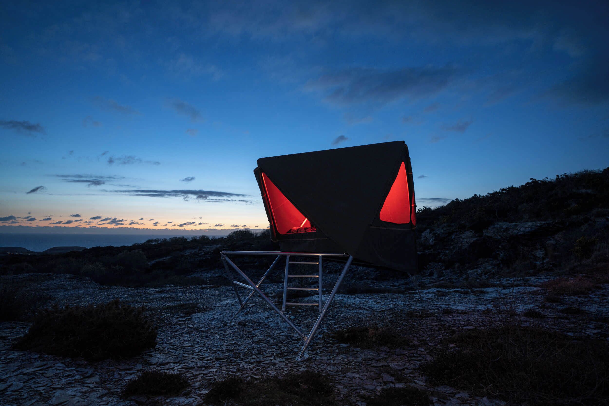 A chair with a unique design, placed on a rocky terrain with a clear sky in the background.