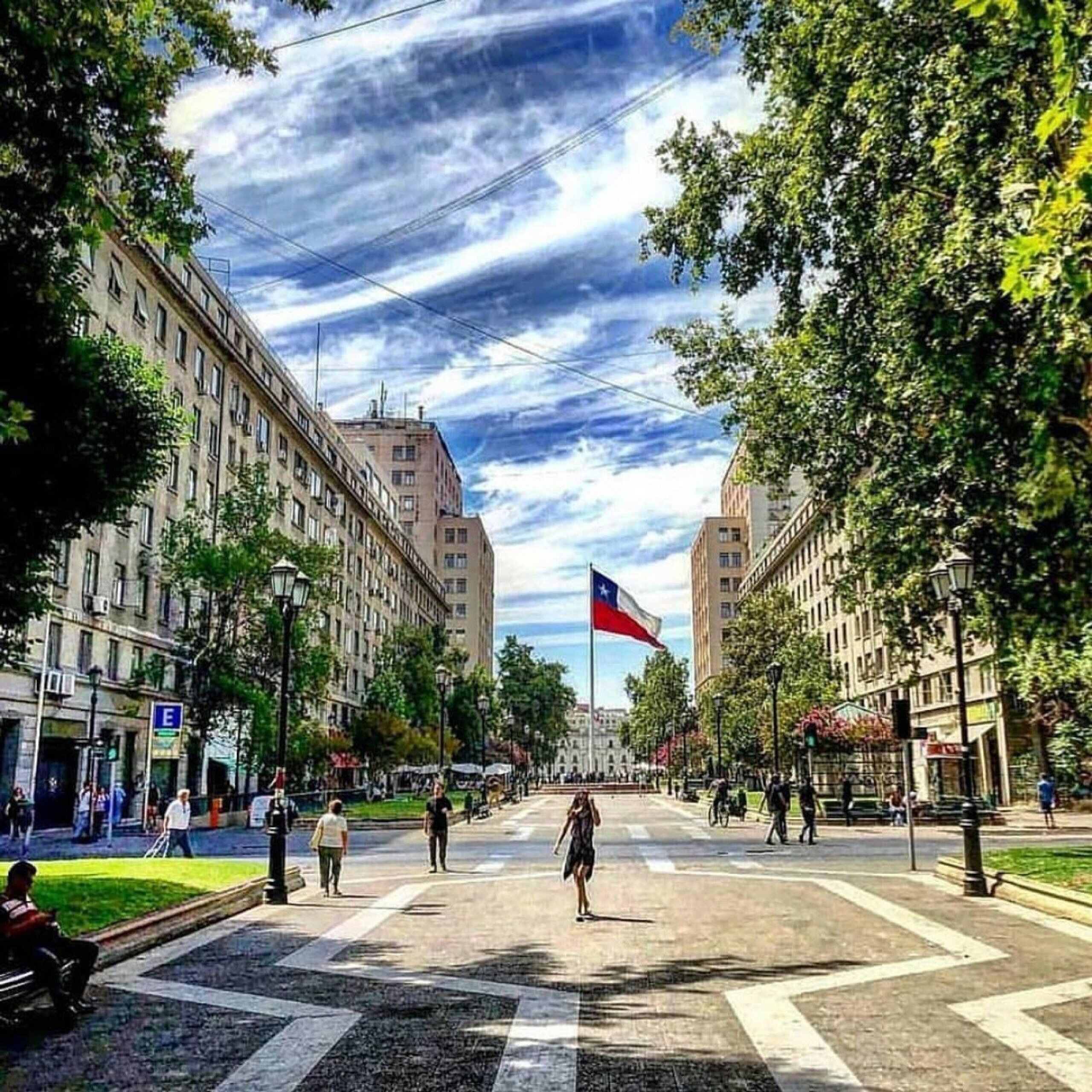 A city street with buildings, a flag, and pedestrians.