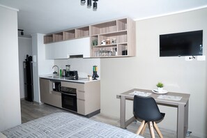 A compact kitchen with a built-in oven, a coffee machine, and a small dining area with a table and chair. - Condor 1152 (Santiago)