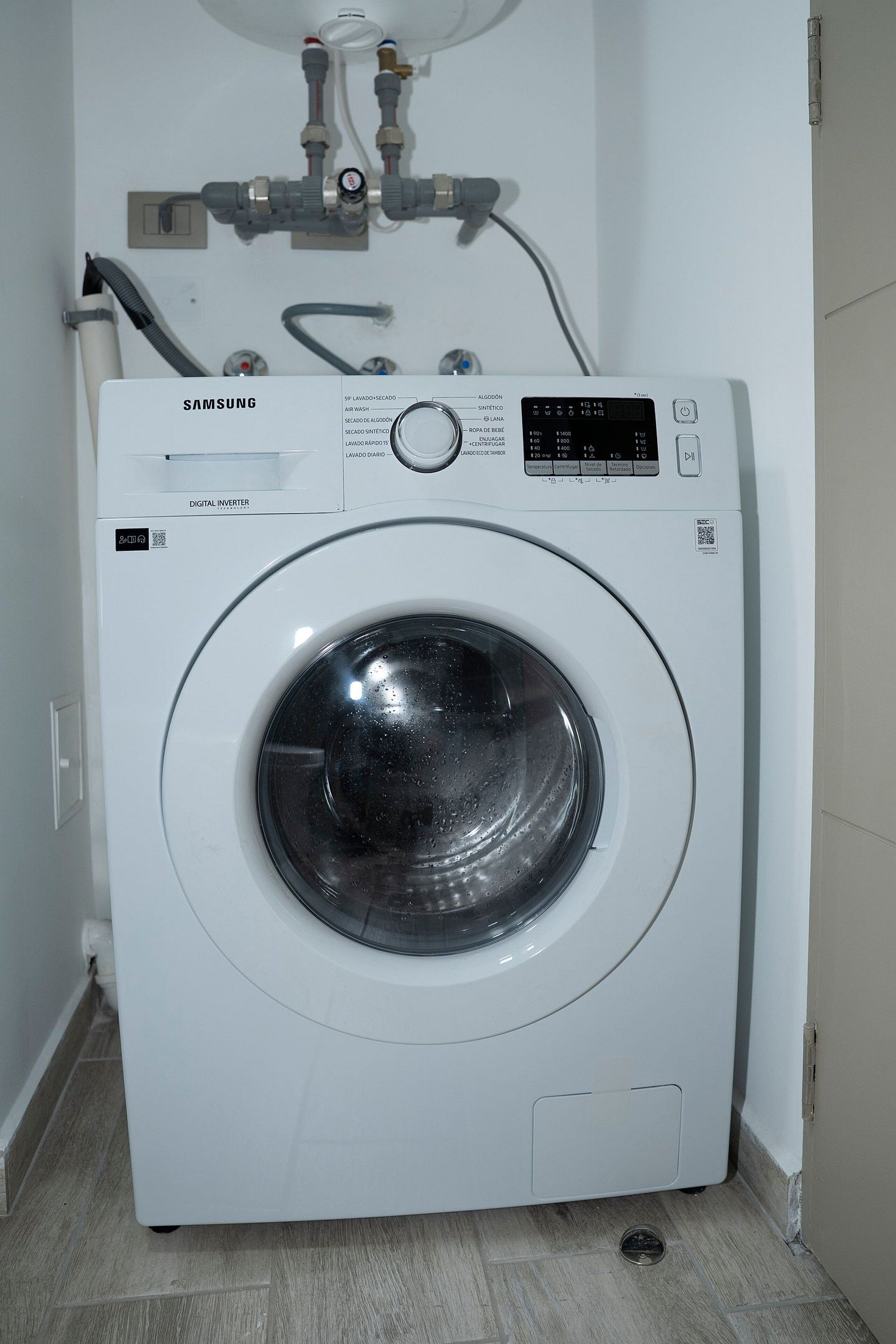 Eine Samsung Digital Inverter Waschmaschine mit Bedienfeld, Wasseranschluss und Schlauch.